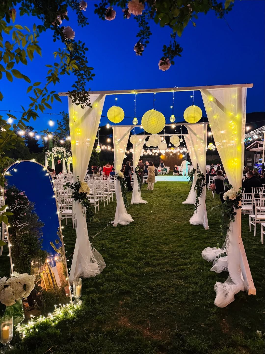 Ceremony aisle lined with tulle and lanterns at dusk